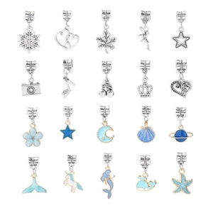 Macro view of blue enamel and silver alloy DIY charms including snowflakes and mermaids