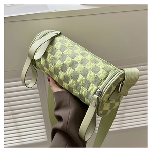 Detail of light green checkered bubble texture on a cylinder crossbody bag with zipper