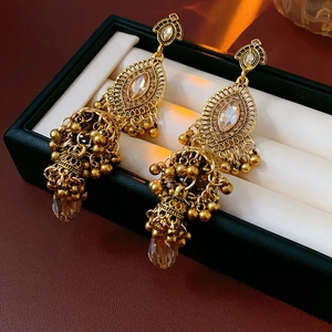 Détail de boucles d'oreilles Jhumka vintage dorées avec cristaux et perles marron