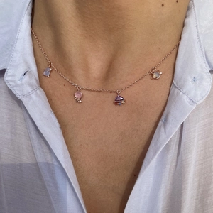 Macro detail of rose gold space theme necklace with astronaut and planet charms on model