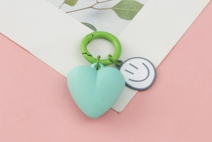 Detail of mint green 3D heart keychain with cartoon smiley face and green buckle