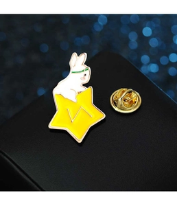 Macro shot of an enamel rabbit brooch sitting on a yellow star with a gold-tone metal finish