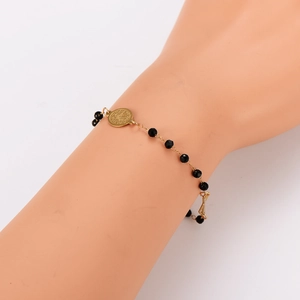 Vintage black beaded bracelet with gold coin pendant on a woman's wrist
