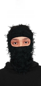 Close-up of black knitted balaclava with distressed tassel fringe and warm eye-opening