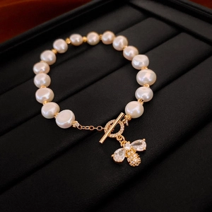 Détail du bracelet en perles plaqué or avec pendentif abeille en zircon et fermoir OT