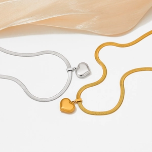 Flache Ansicht von Gold- und Silber-Herzanhängern an Schlangenketten auf Seidenhintergrund