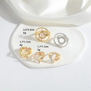 Set of 5 geometric gold and silver open rings with dimensions on white ceramic tray