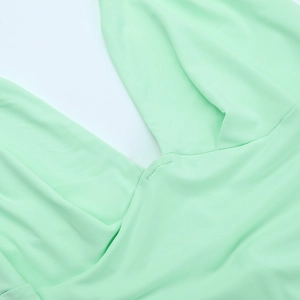 Détail du décolleté en V profond sur cette robe longue dos nu vert menthe au tissu lisse