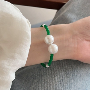 Detail view of retro green glass beads and white imitation pearls on an open cuff bracelet