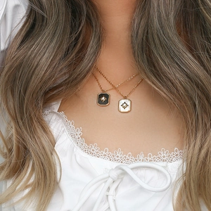 Close-up of gold chain necklaces with black and pearl white octagram star square pendants