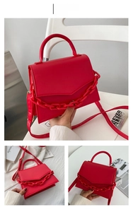 Detail of red synthetic leather crossbody bag with bold plastic chain decoration
