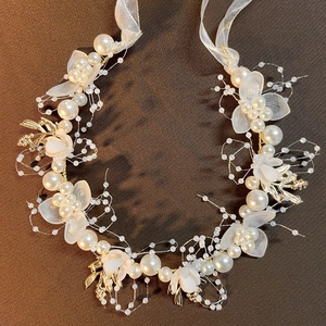 Elegant kids gold leaf headband with white pearls and floral petals on a dark background