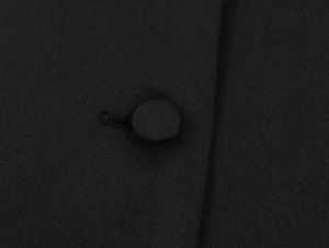 Macro shot of a black fabric covered button and twill texture on elegant blazer jacket
