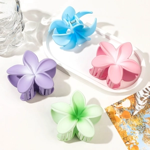 Detail of matte frangipani flower hair claws in purple, blue, pink, and green colors