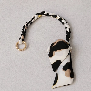 Detail of silk scarf bag strap with leopard print, gold metal ring, and bow accent