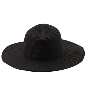 Detail of black wide-brimmed straw hat showing the intricate spiral woven texture