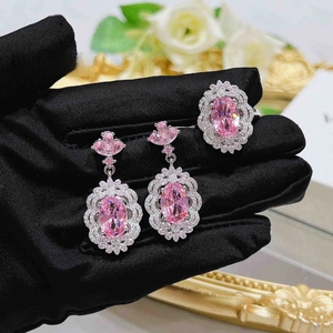 Macro detail of luxury pink zircon earrings and ring set on black velvet background