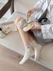 Detail of knit socks featuring colorful stripes and cute dog embroidery in soft tones