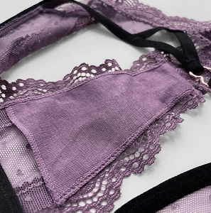Macro shot of purple lace underwear with black elastic straps and a metal heart detail