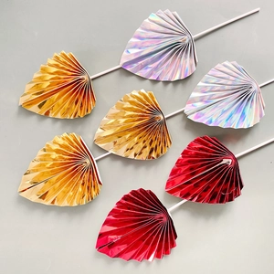 Macro shot of 7 metallic shiny folding fan cake toppers in gold, silver, and red colors