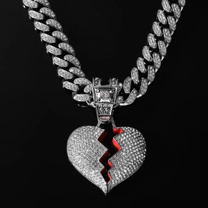 Close-up of iced out Cuban link chain with a red broken heart pendant on black background