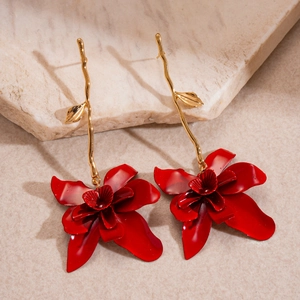 Detail view of long vintage gold branch earrings with vibrant red spray-painted metal flowers
