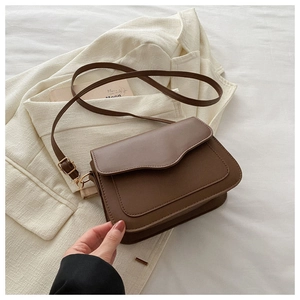 Detail of vintage brown crossbody bag with wave edges and adjustable strap on a minimalist background