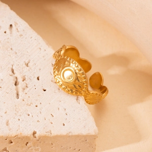 Detail of adjustable gold titanium ring with sun pattern on beige stone base