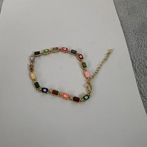 Macro detail of colorful evil eye enamel charms on 14K gold plated bracelet
