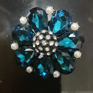 Detailed close-up of blue crystal flower brooch with white pearls and sparkling rhinestones