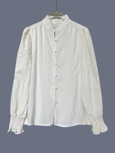 Close-up of white embroidered lace shirt with stand collar and ruffled long sleeve cuffs