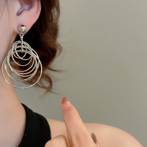 Macro detail of layered silver hoop earrings with a metallic finish on a model