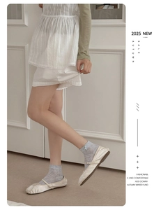 Detail of cream ballet flats with bow and lace socks in a minimalist indoor setting