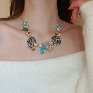 Close-up of a gold starfish and shell necklace set with pearls on a professional model