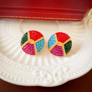 Macro shot of vintage round earrings with multicolored rhinestones on a white plate