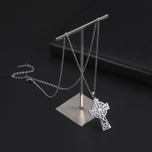 Macro detail of silver Celtic cross pendant hanging on a metal T-bar stand