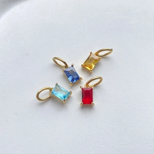 Gros plan de pendentifs rectangulaires en zircon rouge, jaune et bleu avec monture dorée