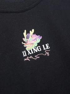 Primer plano de sudadera negra con estampado de dragón colorido y texto XI XING LE