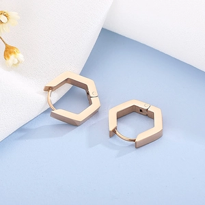 Gros plan sur des créoles hexagonales minimalistes en or rose au fini métal poli