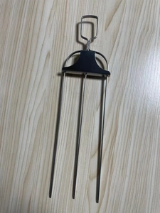 Close-up of stainless steel three-prong barbecue fork with metal handle on wood background