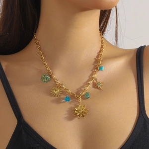 Gold chain necklace with daisy, star, and blue rose pendants worn by a model