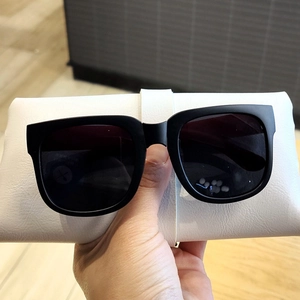 Détail de lunettes de soleil carrées noir mat pour enfants avec étui pliable en cuir blanc