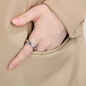 Detailed close-up of a silver-tone wide band ring with zircons on a model's hand