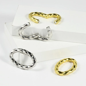 Twisted rope design steel and gold hoop earrings with magnetic clasp on a white stage