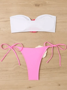 Detailed flat lay of a contrast two-piece bikini with 3D floral accents on wooden background