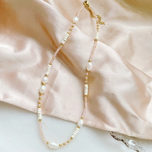Detailed shot of baroque pearls and colorful beads necklace on champagne silk fabric