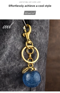 Detailed close-up of a sparkling dark blue apple keychain with golden clasp and ring