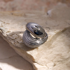 Detail of silver irregular ring with liquid metal finish on a textured stone surface