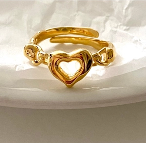 Detail of S925 sterling silver heart ring with chain design on wrinkled paper