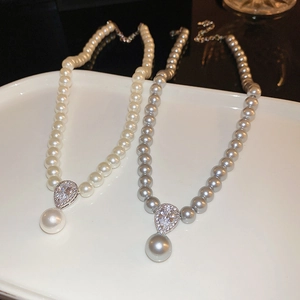 Detail of white and silver grey pearl necklaces with teardrop diamond-set pendants on a tray
